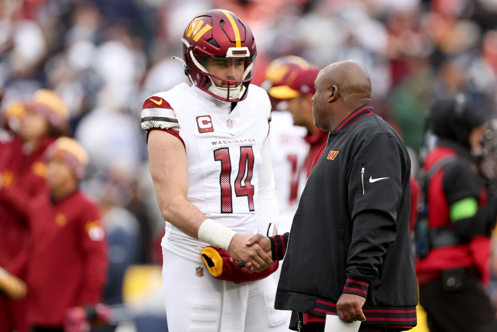 Sam Howell, número 14 de los Washington Commanders, habla con Eric Bieniemy antes del partido