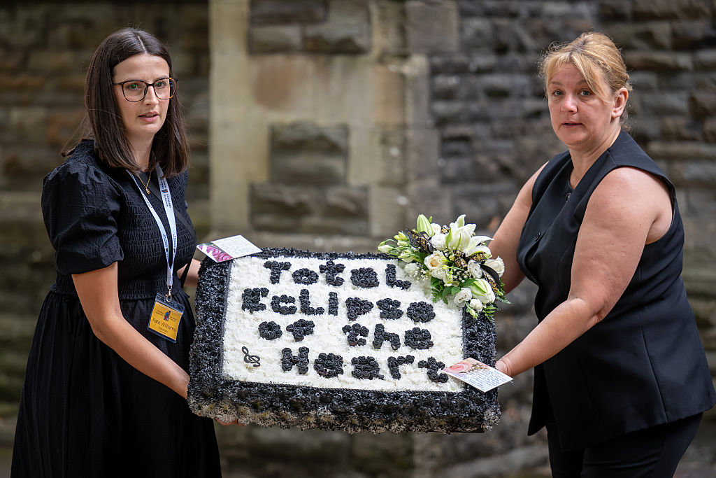 Un arreglo floral con la inscripción "eclipse total del corazón" es llevado antes del funeral de Bonnie Tyler